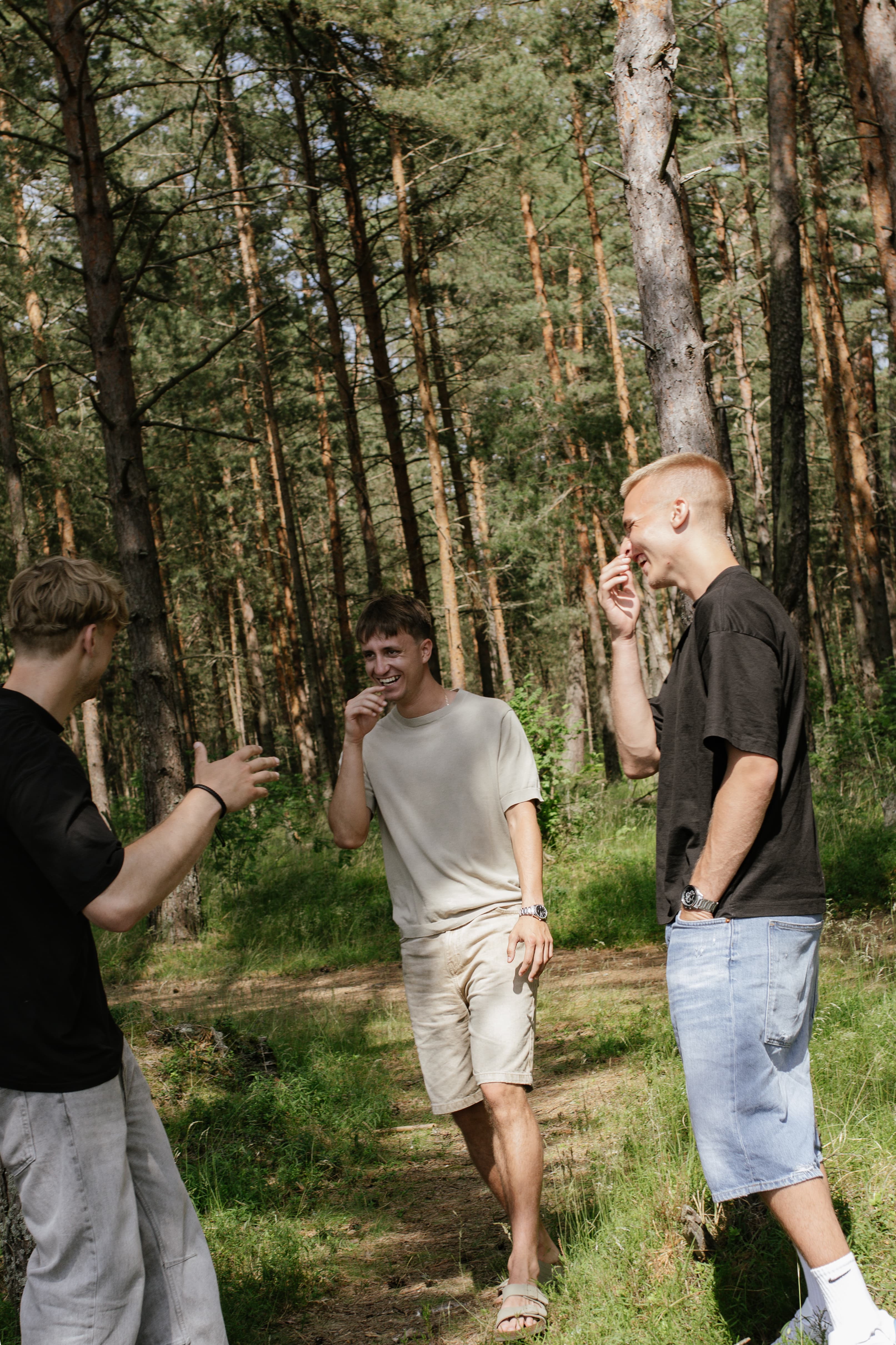 Visi trīs dibinātāji bērzu mežā smaidot un smejoties